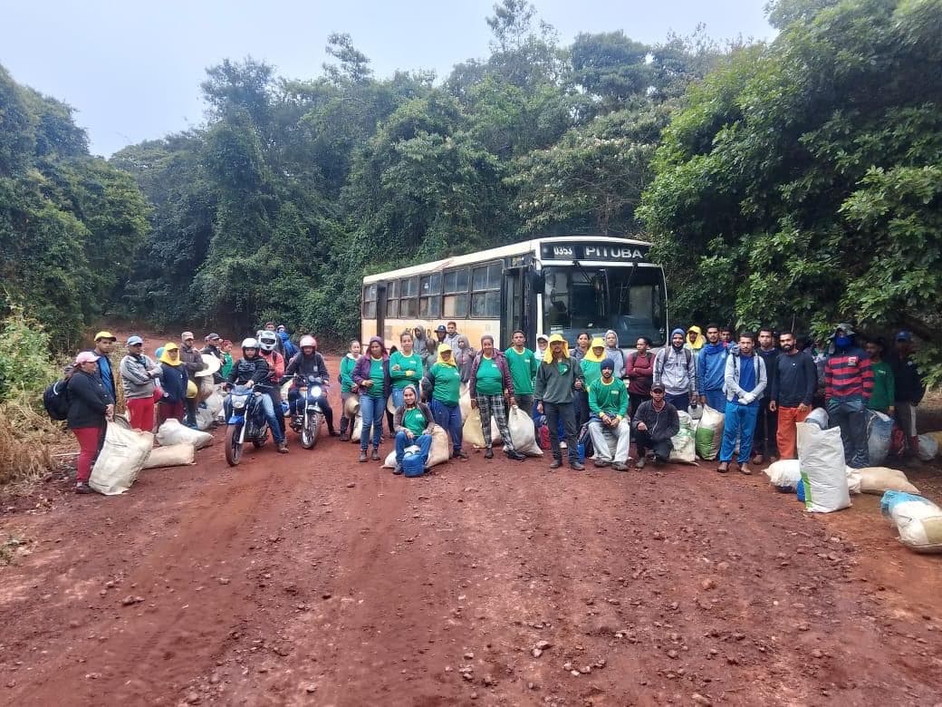 Equipe de cooperados da AGROCOOP Sertão reunida ao lado do ônibus na estrada da lavoura de café